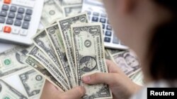 Seorang perempuan memegang uang kertas dolar AS dalam sebuah ilustrasi yang diambil pada 30 Mei 2022. (Foto: REUTERS/Dado Ruvic)