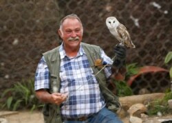 Gary Strafford, a Zimbabwean falconer, holds an owl inside one of the cages at his bird sanctuary, Kuimba Shiri, near Harare, Zimbabwe, June 17, 2020.