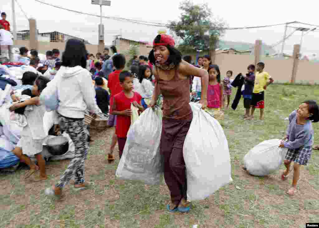 Residents carry sacks of donated clothes at an evacuation center for the coastal community to take shelter from Typhoon Hagupit in Manila, Dec. 8, 2014.