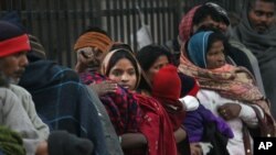 FILE - Indian homeless people wait for free food outside a temple, in New Delhi, India, Jan. 1, 2013.