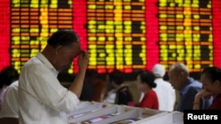 Investors look at computer screens showing stock information at a brokerage house in Shanghai, China, July 8, 2015.