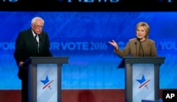 Bernie Sanders, left, listens as Hillary Clinton speaks during a Democratic presidential primary debate at Saint Anselm College in Manchester, N.H., Dec. 19, 2015.