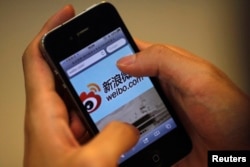 FILE - A man holds an iPhone as he visits Sina's Weibo microblogging site in Shanghai, May 29, 2012.