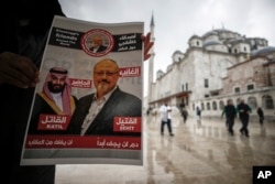 FILE - A man holds a poster showing images of Saudi Crown Prince Muhammed bin Salman (L), dubbed "assassin," and of journalist writer Jamal Khashoggi, dubbed "martyr," during a prayer service for Khashoggi, in Istanbul, Turkey, Nov. 16, 2018.