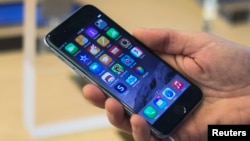 FILE - A customer holds an iPhone 6 on display at the Fifth Avenue Apple store on the first day of sales in Manhattan, New York, Sept. 19, 2014. 