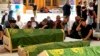 Des personnes en deuil prient près des cercueils des patients atteints de coronavirus qui ont été tués dans l'incendie d'un hôpital, à Najaf, en Irak, dimanche 25 avril 2021.