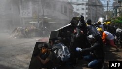 Protesters take shelter behind homemade shields after tear gas was fired during a demonstration against the military coup in Yangon on March 8, 2021.