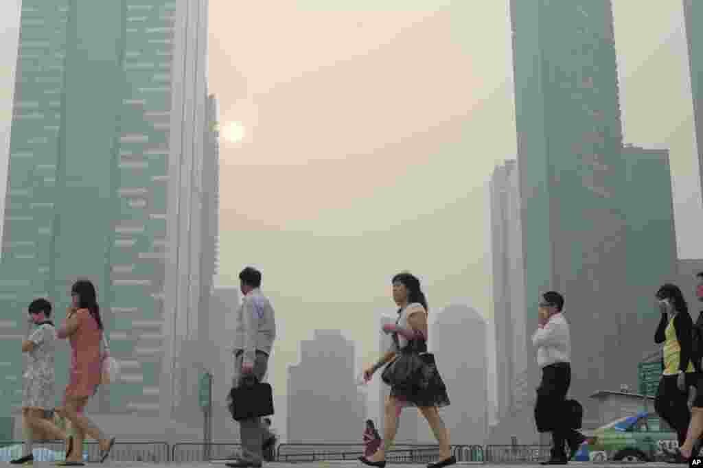Pekerja kantoran di Singapura berjalan menuju tempat kerja di tengah kabut asap (20/6). (AP/Joseph Nair)
