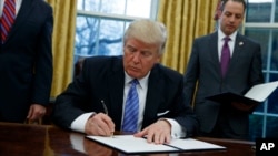 FILE - President Donald Trump signs an executive order in the Oval Office of the White House, Jan. 23, 2017. Trump is expected to sign several executive orders on energy and the environment this week.