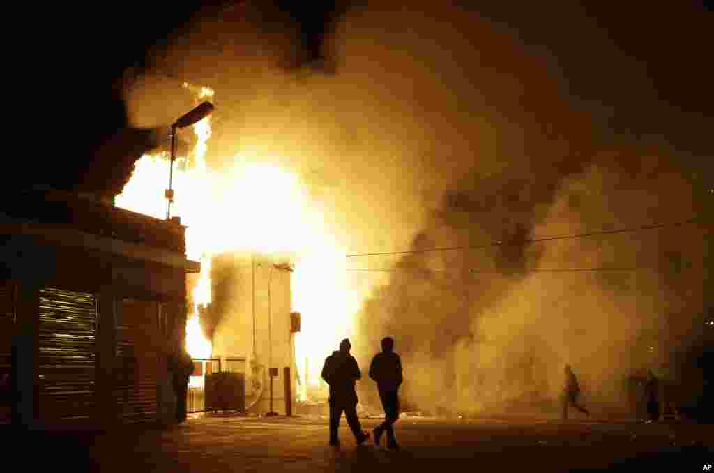 Warga menjauhi gudang yang terbakar menyusul kerusuhan setelah pengumuman dewan juri pengadilan Missouri, Senin (24/11) di Ferguson, Missouri.&nbsp;(AP/Jeff Roberson)