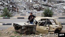A Palestinian child stands inside a damaged car in front of a destroyed building in the war-devastated Bureij refugee camp in the central Gaza Strip on Feb. 7, 2025. 