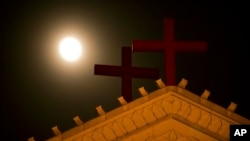 FILE - The moon rises above a pair of crosses on the roof of Holy Trinity Church in Wenzhou in eastern China's Zhejiang Province.