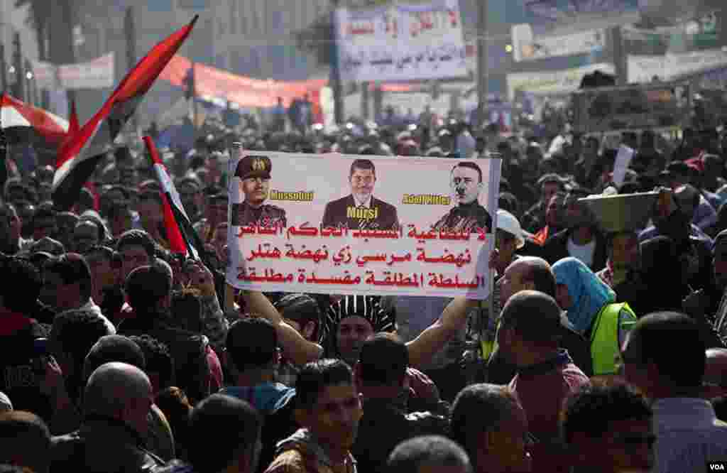 A protester on Tahrir Square holds up a poster comparing Egyptian President Mohamed Morsi to former fascist leaders Benito Mussolini and Adolf Hitler, November 30, 2012. (Y. Weeks/VOA)