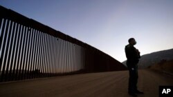 FILE - Border Patrol agent Justin Castrejon stands in front of newly replaced border wall sections, near Tecate, California, Sept. 24, 2020.