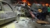 Men gather near burning cars at the site of an explosion in Beirut's southern suburbs, July 9, 2013.