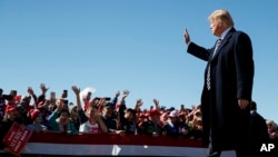 President Donald Trump waves as he walks from the stage at Elko Regional Airport, Oct. 20, 2018, in Elko, Nev., after speaking during a campaign rally. 