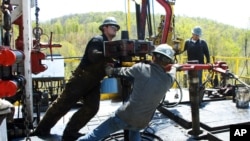 FILE - Workers move a section of well casing into place at a Chesapeake Energy natural gas well site near Burlington, Pa., April 23, 2010.