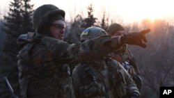 FILE - Fighters of the Azov Battalion observe enemy lines from the roof of their base in the town of Shyrokyne, eastern Ukraine, March 22, 2015. 