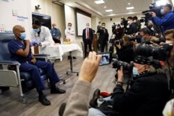 FILE - Members of the media are seen as a medical worker is inoculated with the Pfizer coronavirus vaccine, in New Hyde Park, New York, Dec. 14, 2020.