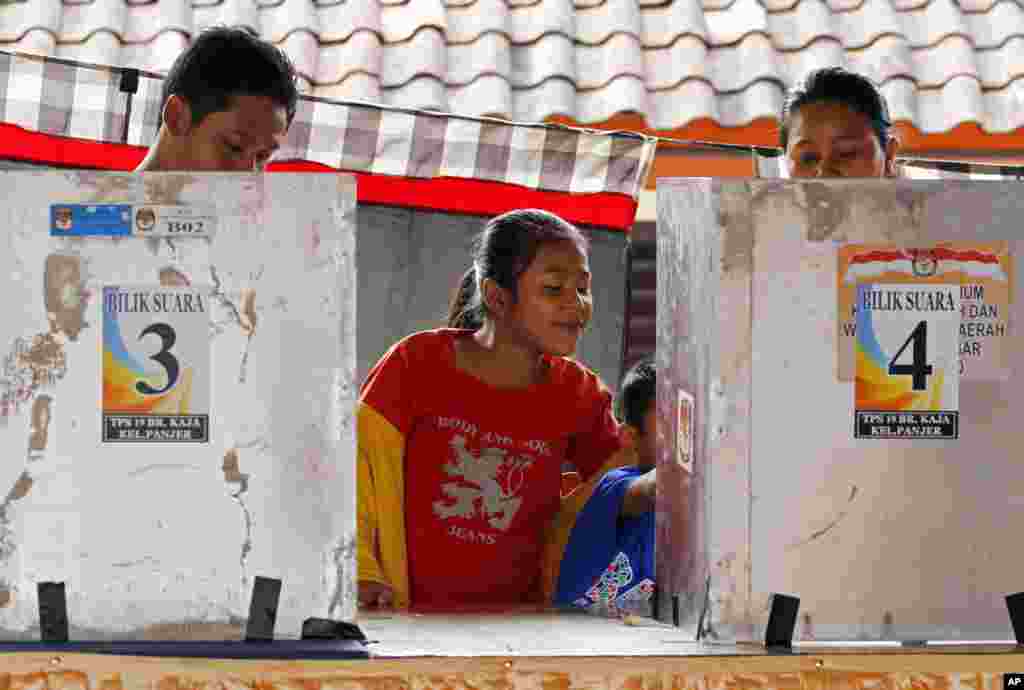 Anak-anak menunggu orangtuanya memilih di sebuah TPS di Bali (9/7). (AP/Firdia Lisnawati)