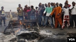 Pendukung presiden Alassane Ouattara menunjuk mayat yang terbakar yang diyakini sebagai pendukung Laurent Gbagbo, di Distrik Abobo, Abidjan (7/3).