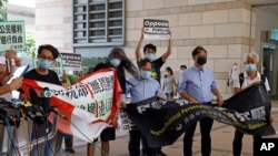 Pro-democracy activists including Leung Kwok-hung, second left, hold banners outside a district court in Hong Kong, July 30, 2020. 