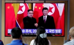 People watch a TV program about Chinese President Xi Jinping's state visit to North Korea with a file footage of Chinese President Xi Jinping and North Korean leader Kim Jong Un, June 18, 2019, at the Seoul Railway Station in Seoul, South, Korea.