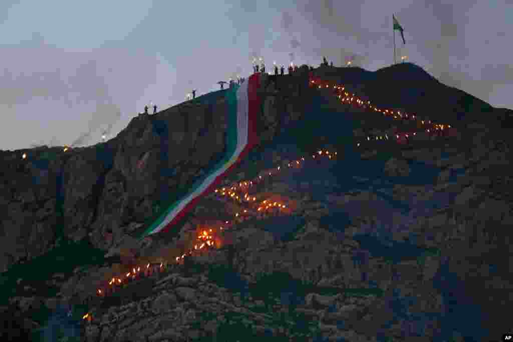 Warga Kurdi Irak dengan spanduk raksasa dalam warna bendera Kurdi merayakan Nawruz, atau tahun baru, di Dahuk, 260 km (430 kilometer) di sebelah barat laut Baghdad, Irak. Perayaan Nawruz berakar pada masa&nbsp; Zoroaster untuk menandai datangnya musim semi dan perayaan awal tahun baru bagi orang Kurdi seluruh dunia. 