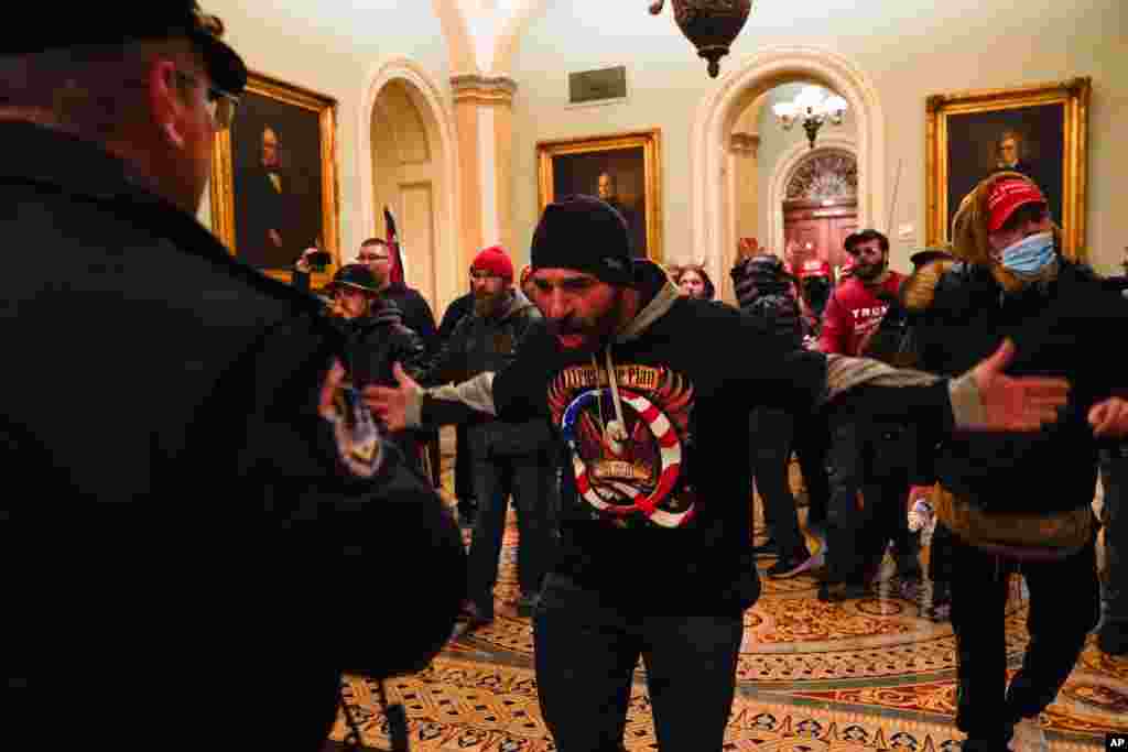 Protesters gesture to U.S. Capitol Police in the hallway outside of the Senate chamber at the Capitol in Washington, Jan. 6, 2021, near the Ohio Clock. 