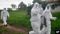 Des agents de la santé amenant au laboratoire un échantillon de sang prélevé sur un malade présumé victime de l'Ebola, près de Monrovia, au Libéria (AP Photo/ Abbas Dulleh)