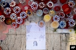 FILE - Candles, notes and paper cuttings lie next to the "Love Monument" in St. Julian, Malta, Oct. 17, 2017, the day after the killing of journalist Daphne Caruana Galizia.