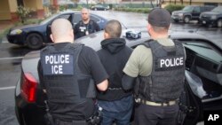 FILE - This photo released by U.S. Immigration and Customs Enforcement shows foreign nationals being arrested during a targeted enforcement operation aimed at immigration fugitives, re-entrants and at-large criminal aliens in Los Angeles, Feb. 7, 2017. 