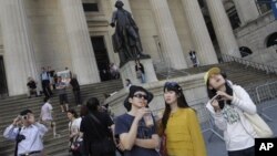 Wisatawan dari Tiongkok di depan gedung Bursa Efek New York (NYSE) (Foto: dok). Permintaan visa kunjungan ke Amerika meningkat lebih dari 43 persen dibanding kurun waktu yang sama tahun fiskal yang lalu.