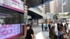 2021年2月22日人们走过显示香港股票指数的银行电子板。