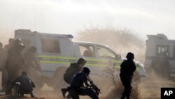 Polisi di tengah-tengah gas air mata dan debu mengarahkan tembakan ke arah para pekerja di pertambangan Lonmin di Rustenburg (16/8). 