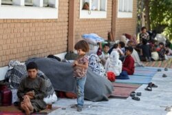 FILE - Internally displaced Afghan families, who fled from the northern province due to battle between Taliban and Afghan security forces, sit in the courtyard of the Wazir Akbar Khan mosque in Kabul, August 13, 2021.