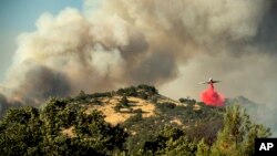 Sebuah pesawat menyemprotkan bahan pemadam api di atas kebakaran lahan di Spring Lakes, 24 Juni 2018., dekat Clearlake Oaks, California. 