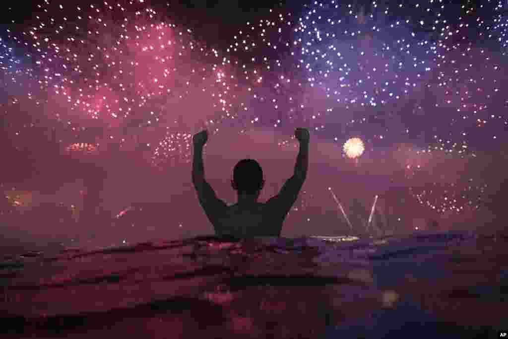 A man watches the fireworks exploding over Copacabana Beach during the New Year's celebrations in Rio de Janeiro, Brazil, Jan. 1, 2019. 