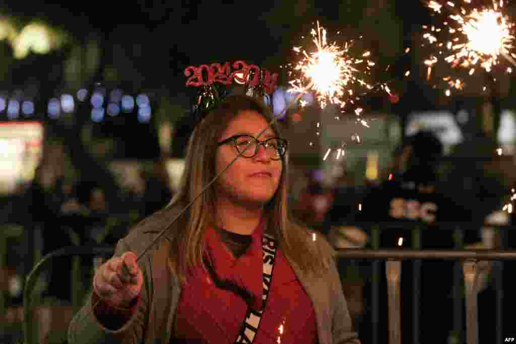 A woman holds a sparkler during the concert of Panamanian musician, singer and politician Ruben Blades at the monument Angel de la Independencia during the New Year 2024 celebration in Mexico City, Dec. 31, 2023.