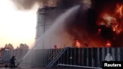 Anggota kementerian darurat Rusia berupaya memadamkan api dari tangki penyimpanan minyak setelah dugaan serangan drone di kota Azov, wilayah selatan Rostov, Rusia, 18 Juni 2024, dalam gambar yang diambil dari video. (Kementerian Keadaan Darurat Rusia/Handout via REUTERS)