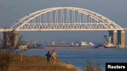 FILE - A Russian cargo ship is seen beneath a bridge connecting the Russian mainland with the Crimean Peninsula after three Ukrainian navy vessels were stopped by Russia from entering the Sea of Azov via the Kerch Strait in the Black Sea, Crimea, Nov. 25, 2018.