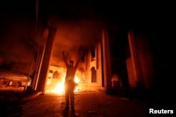 FILE - An Iraqi protester gestures in front of the burned Iranian consulate in Basra, Iraq, Sept. 7, 2018.