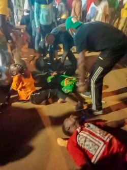 People assist victims of a stampede outside a stadium hosting a soccer game in Yaounde, Cameroon, Jan. 24, 2022.