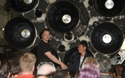 FILE - SpaceX CEO Elon Musk (L) shakes hands with Japanese billionaire Yusaku Maezawa during a press conference about being the first SpaceX private passenger to circle the moon aboard SpaceX’s BFR launch vehicle, in Hawthorne, California on Sept. 17, 2018.