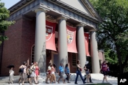 FILE - A tour group walks through the campus of Harvard University in Cambridge, Mass.
