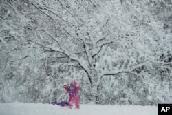 A young girl plays in the snow during a winter storm, March 7, 2018, in Marple Township, Pennsylvania.