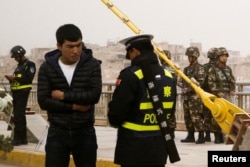 A police officer checks the identity card of a man as security forces keep watch in a street in Kashgar, Xinjiang Uighur Autonomous Region, China, March 24, 2017.