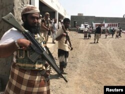 FILE - Yemeni fighters secure a building where UAE Red Crescent distribute aid to displaced people in Al-Mokha, Yemen, March 6, 2018.