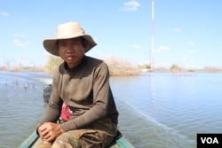 លោក ហ្វុត ឃឿន អាយុ៣៩ឆ្នាំ ដែល​ជា​ប្រជាពលរដ្ឋ​រងគ្រោះ​ដោយសារ​ទំនប់​វារីអគ្គិសនី​សេសានក្រោម២ ខេត្តស្ទឹងត្រែង បើកបរ​ទូក​មើល​ផ្ទះសម្បែង​របស់​ប្រជាពលរដ្ឋ​នៅ​ភូមិស្រែគរ ដែល​ត្រូវបាន​លិចលង់។ (ស៊ុន ណារិន/VOA)