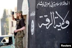 A militant Islamist fighter uses a mobile to film his fellow fighters taking part in a military parade along the streets of Syria's northern Raqqa province. (2014/file)